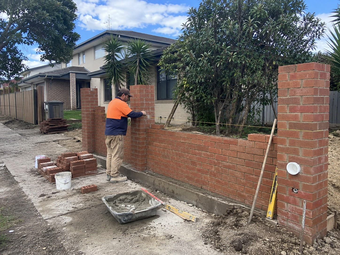 Bricklayer constructing a brick boundary fence with feature pillars at a Perth home